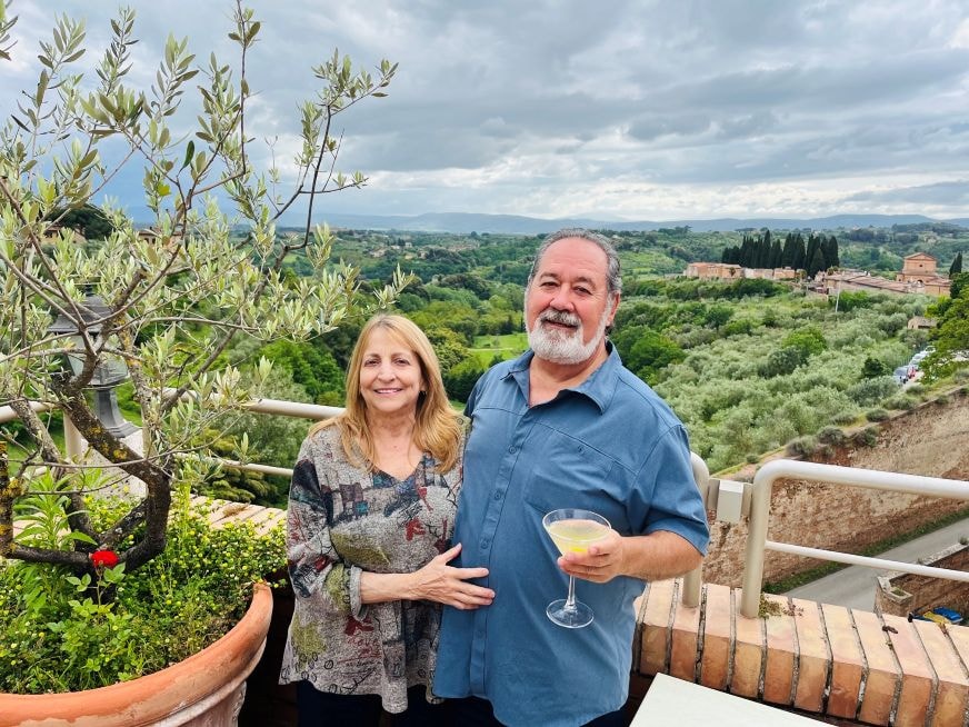 Couple enjoying wine Tuscan countryside hotel balcony Siena